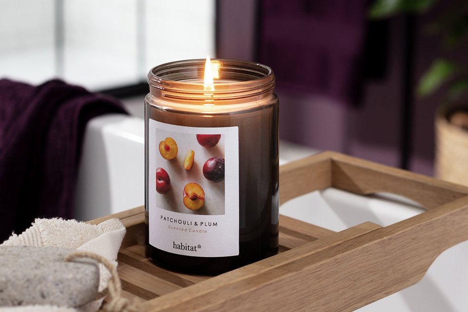 A candle in a jar placed on a tray.